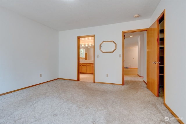 unfurnished bedroom featuring ensuite bathroom and light carpet