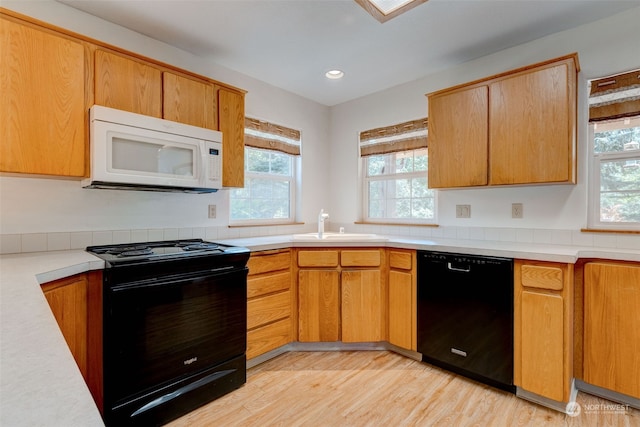 kitchen with light wood-type flooring, sink, and black appliances