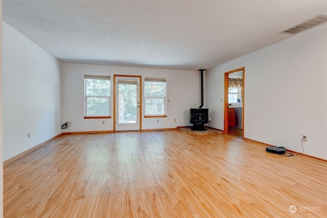 unfurnished living room featuring light hardwood / wood-style flooring and a wood stove