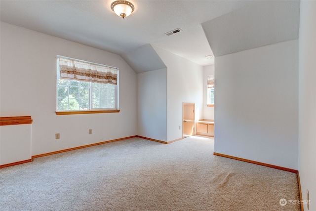 carpeted spare room with a wealth of natural light and vaulted ceiling