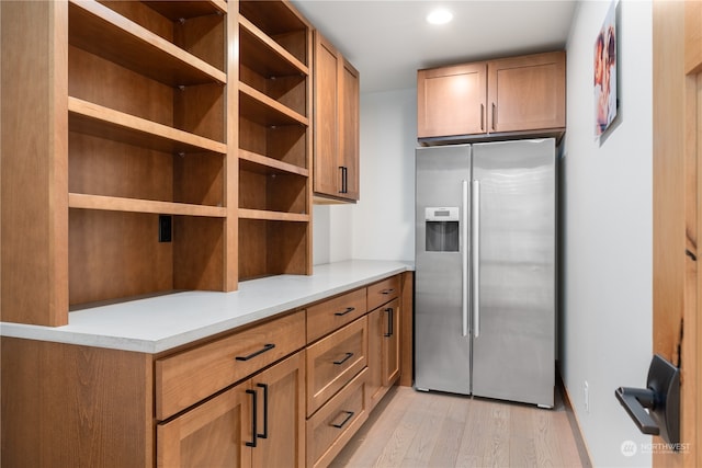 kitchen with light wood-type flooring and stainless steel fridge with ice dispenser