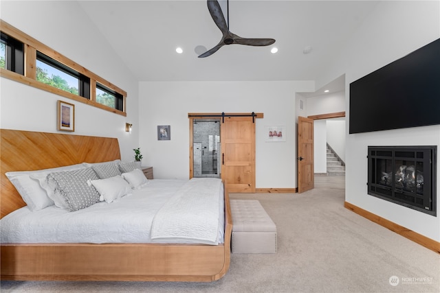 carpeted bedroom with ensuite bath, lofted ceiling, ceiling fan, and a barn door