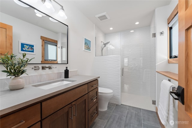 bathroom with vanity, toilet, tile patterned floors, and walk in shower