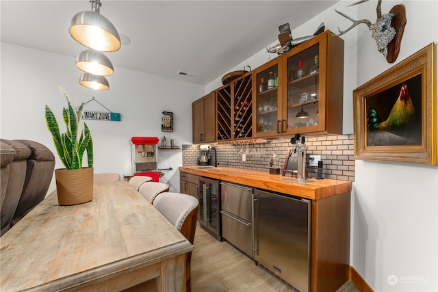 bar with butcher block countertops, light hardwood / wood-style flooring, beverage cooler, tasteful backsplash, and hanging light fixtures