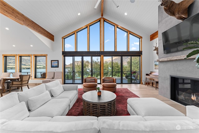 living room featuring high vaulted ceiling, a wealth of natural light, a fireplace, and hardwood / wood-style flooring