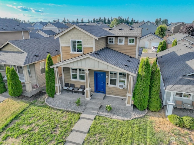 view of front of house featuring a residential view, cooling unit, a porch, and a front yard