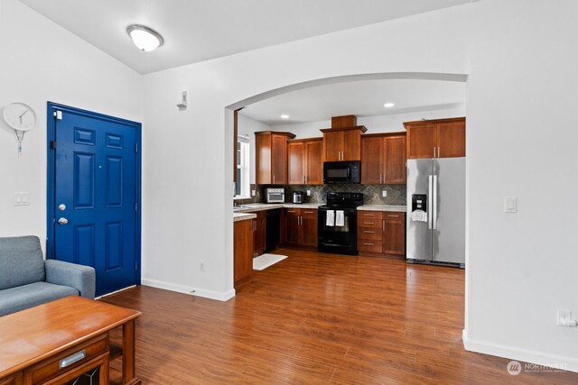 kitchen with black appliances, dark hardwood / wood-style floors, and tasteful backsplash