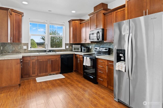 kitchen with sink, black appliances, backsplash, and hardwood / wood-style floors