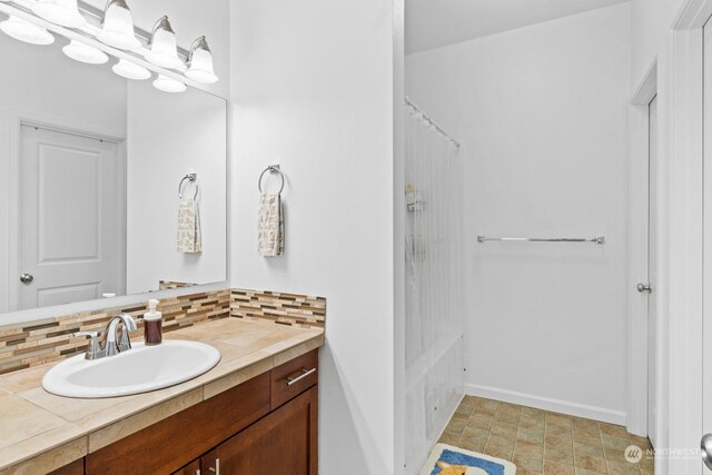 bathroom with tasteful backsplash, tile patterned flooring, and vanity