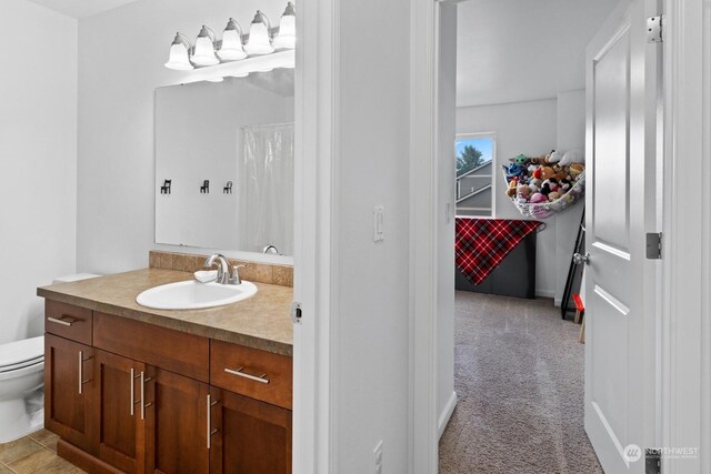 bathroom featuring tile patterned flooring, toilet, and vanity