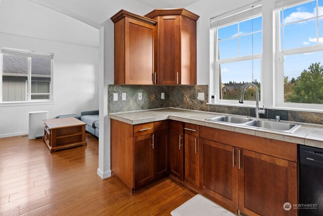 kitchen with dishwashing machine, decorative backsplash, sink, and wood-type flooring