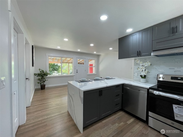 kitchen with light hardwood / wood-style flooring, kitchen peninsula, and appliances with stainless steel finishes