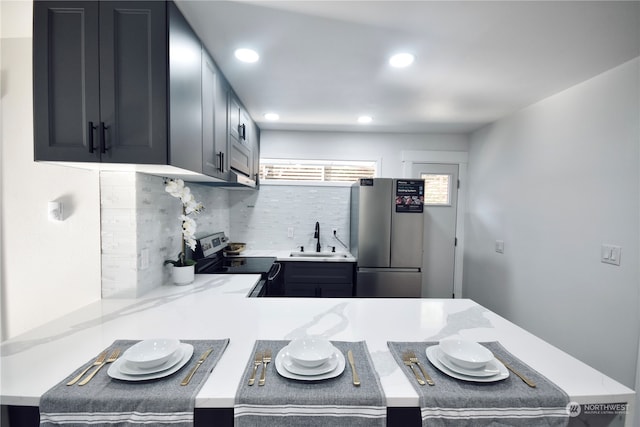 kitchen with light stone counters, stainless steel appliances, sink, and decorative backsplash