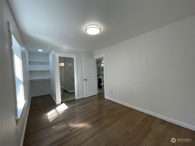 unfurnished bedroom with connected bathroom and dark hardwood / wood-style floors