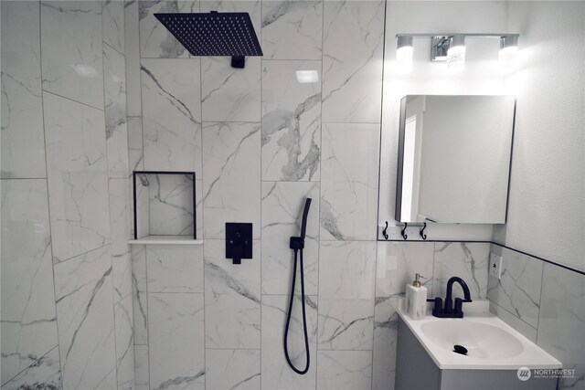 bathroom featuring tiled shower, vanity, and tile walls