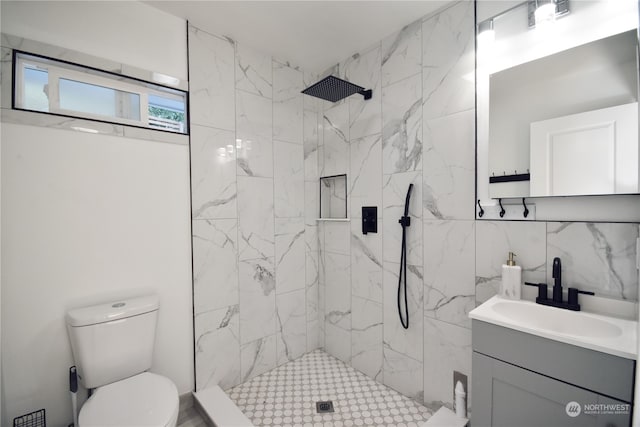 bathroom with vanity, toilet, and tiled shower