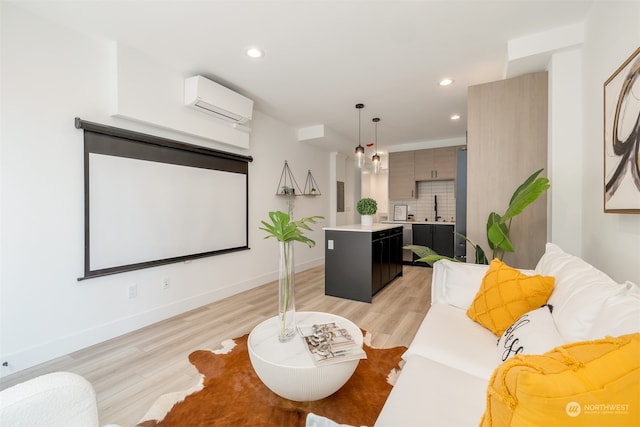 cinema room featuring sink, an AC wall unit, and light wood-type flooring