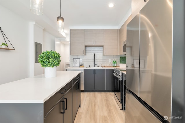 kitchen with light hardwood / wood-style flooring, sink, decorative backsplash, hanging light fixtures, and appliances with stainless steel finishes