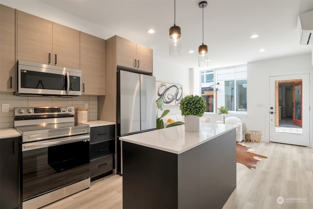 kitchen with a kitchen island, decorative light fixtures, light hardwood / wood-style flooring, appliances with stainless steel finishes, and tasteful backsplash