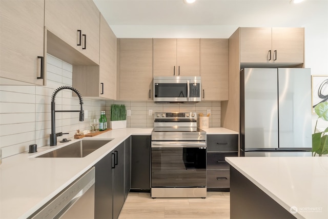 kitchen featuring stainless steel appliances, sink, light brown cabinets, decorative backsplash, and light wood-type flooring