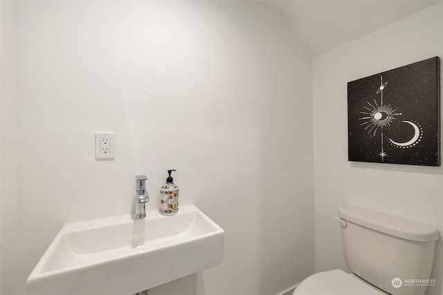 bathroom with lofted ceiling, toilet, and sink