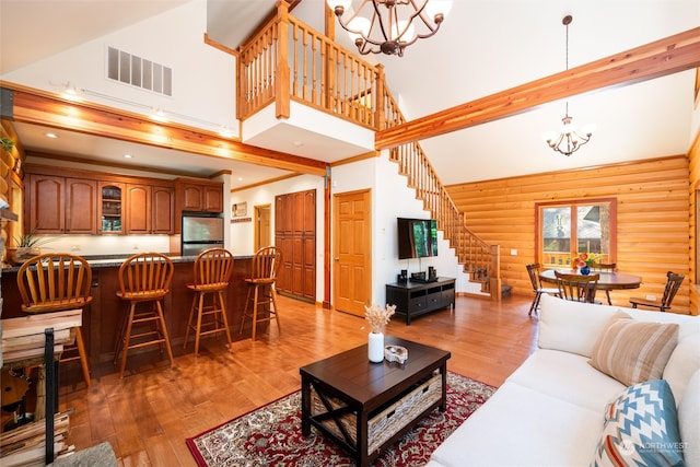 living room featuring hardwood / wood-style flooring, a towering ceiling, rustic walls, and a chandelier