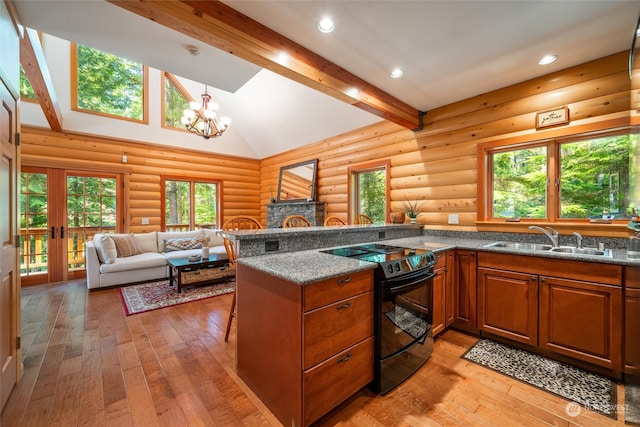 kitchen featuring light wood-type flooring, rustic walls, a chandelier, black electric range oven, and sink