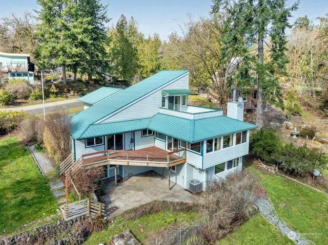 back of house featuring central air condition unit, driveway, a chimney, and metal roof