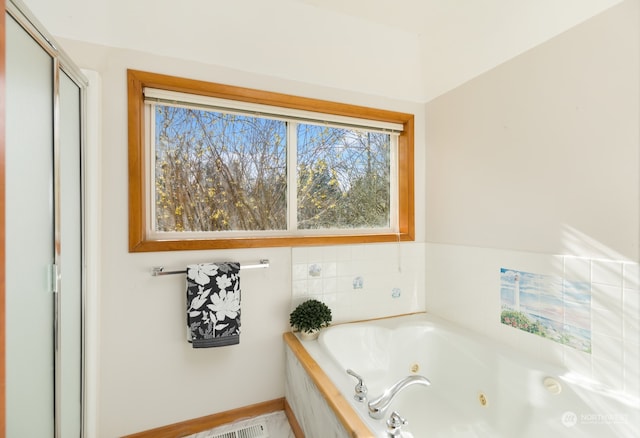 bathroom featuring plenty of natural light and tiled bath