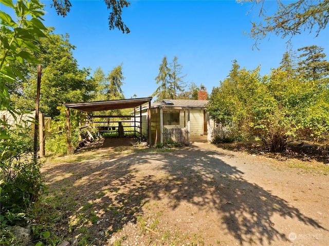 exterior space featuring a carport, driveway, and a chimney