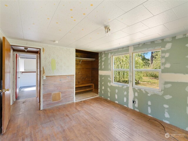 unfurnished room with wood walls and hardwood / wood-style flooring