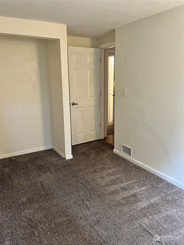 unfurnished bedroom with dark carpet