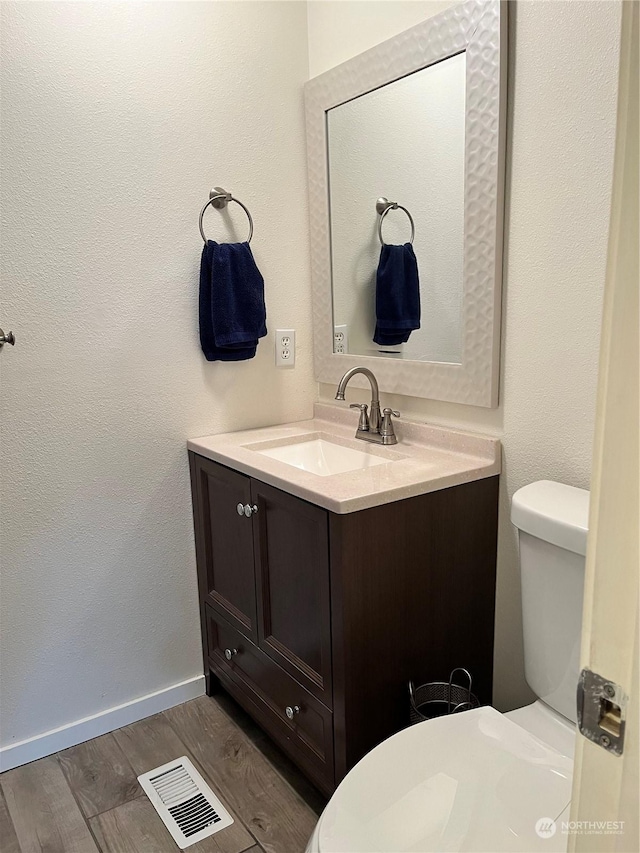 bathroom featuring vanity, wood-type flooring, and toilet