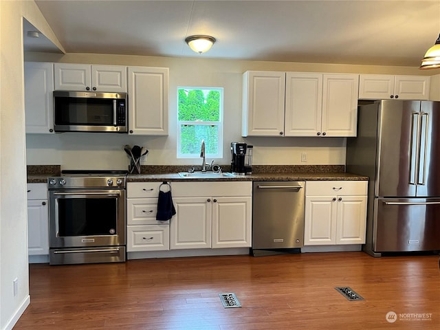 kitchen featuring high quality appliances, sink, dark wood-type flooring, and white cabinets