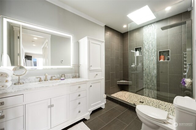 bathroom with tiled shower, crown molding, vanity, and toilet