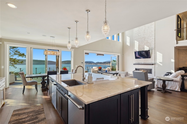 kitchen featuring sink, a fireplace, light stone countertops, dark hardwood / wood-style flooring, and a water view