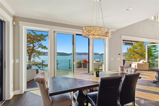 dining space featuring a water view, lofted ceiling, hardwood / wood-style flooring, ornamental molding, and a notable chandelier