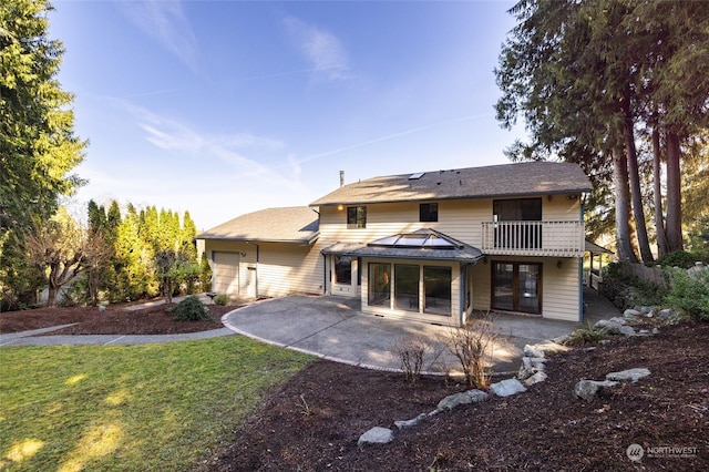 exterior space featuring an attached garage, a patio area, a balcony, and a yard