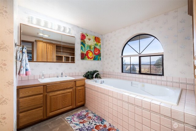 full bath with wallpapered walls, a bath, and vanity