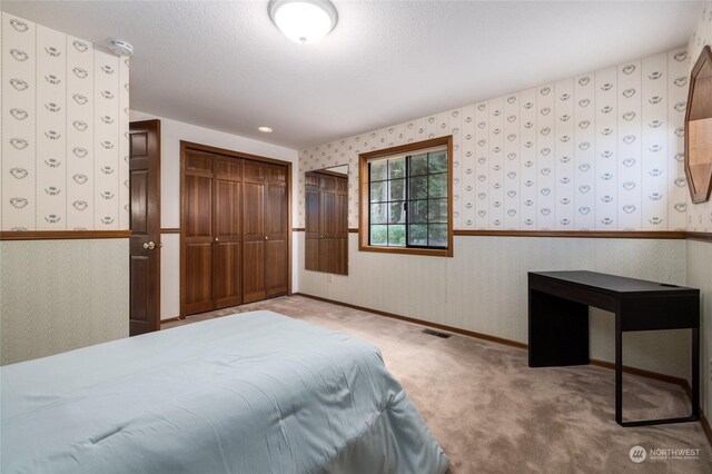 unfurnished bedroom with light carpet, visible vents, baseboards, a closet, and wallpapered walls