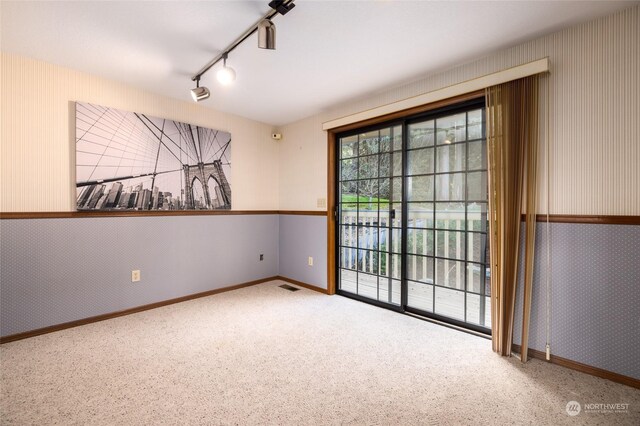 carpeted empty room featuring track lighting