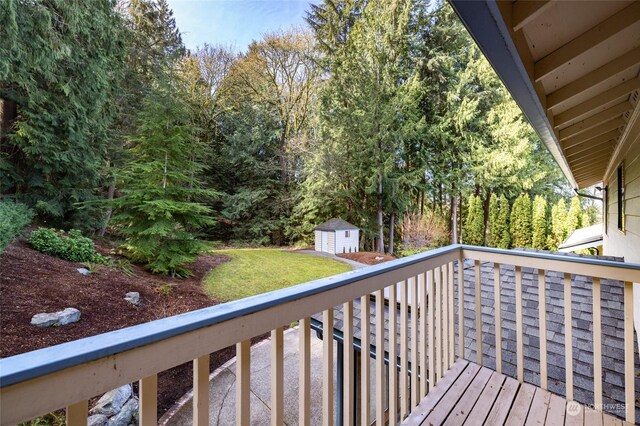 wooden terrace with a storage shed, a lawn, and an outbuilding