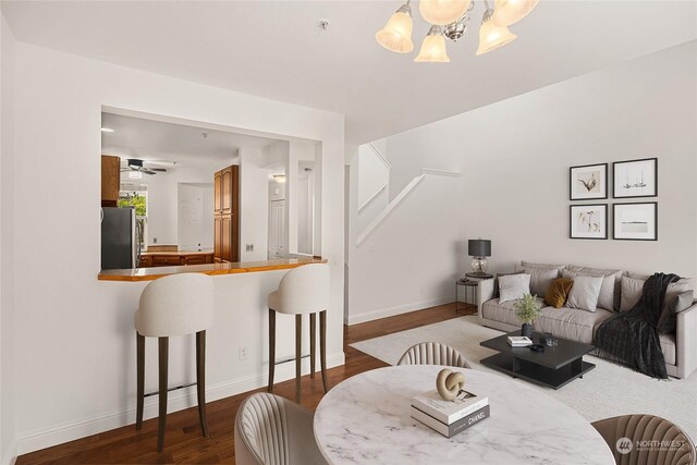 dining space with ceiling fan with notable chandelier and dark wood-type flooring