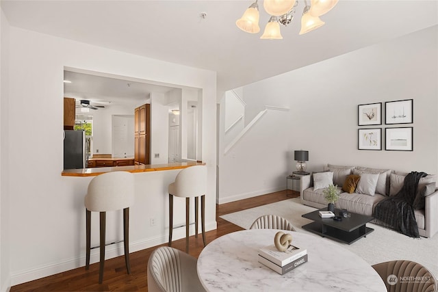 living area featuring a notable chandelier, baseboards, and dark wood-style flooring