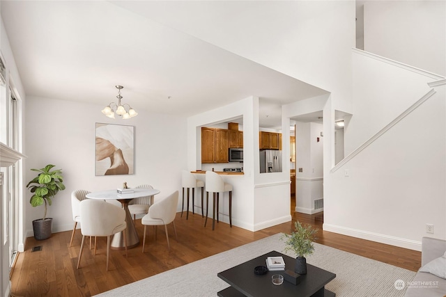 living area featuring baseboards, wood finished floors, visible vents, and an inviting chandelier