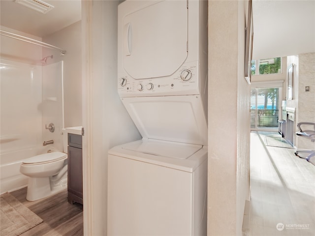 clothes washing area featuring light wood-type flooring and stacked washer / dryer