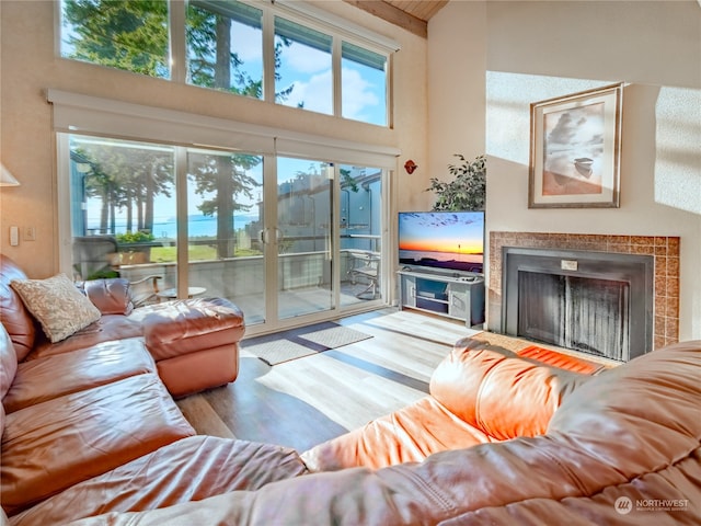 living room with a fireplace, light wood-type flooring, and a high ceiling