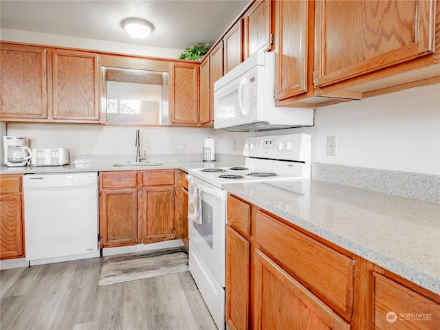 kitchen with sink, white appliances, light hardwood / wood-style floors, and light stone counters