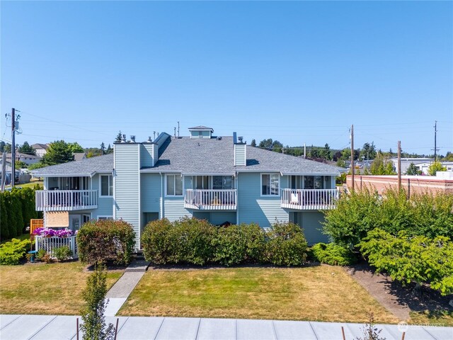 view of front of property featuring a balcony and a front lawn