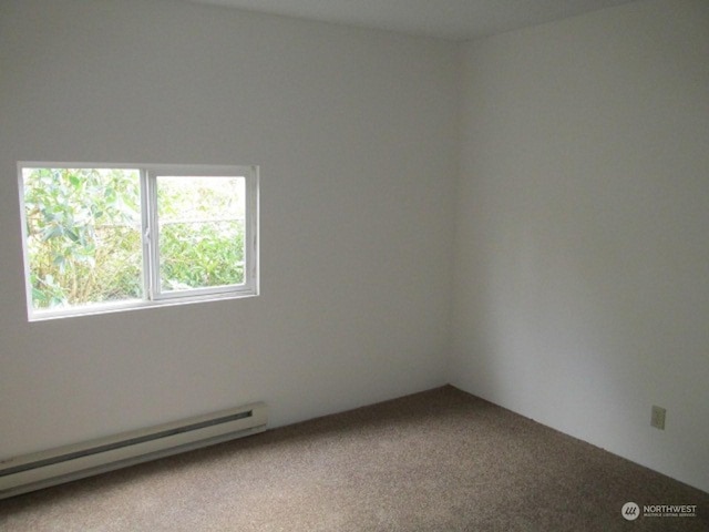 carpeted spare room with a baseboard heating unit